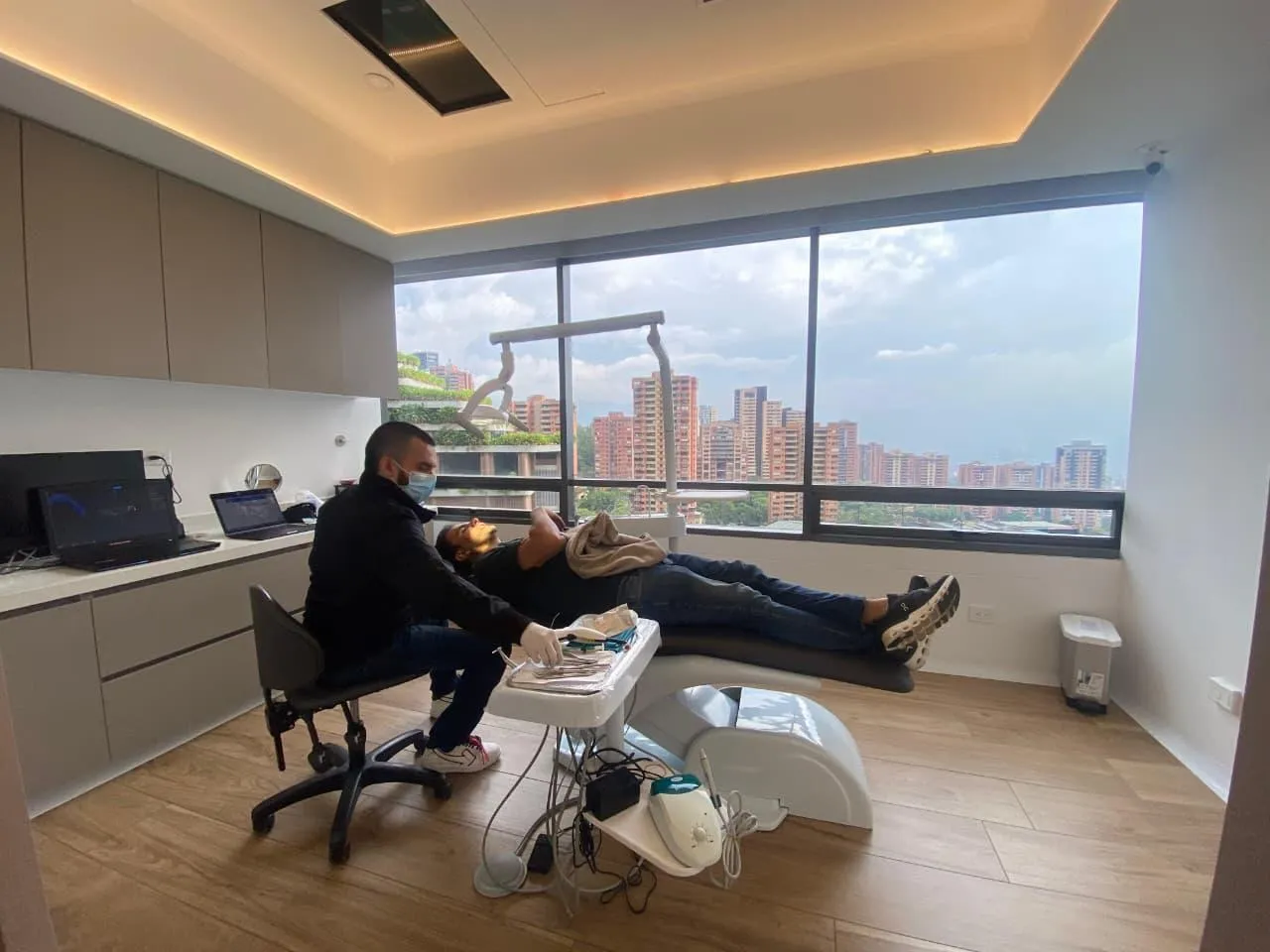 One of our dentists with a patient, with Medellín through the window